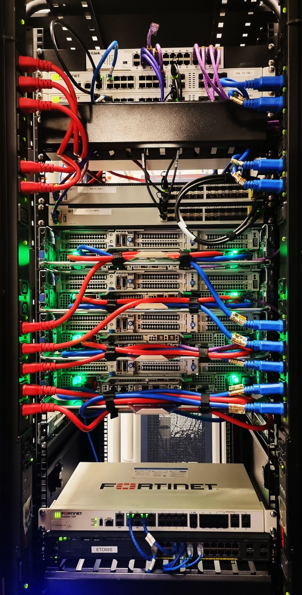 A hyperconverged server rack: red and blue power cables bundled in parallel runs, green status lights on every node